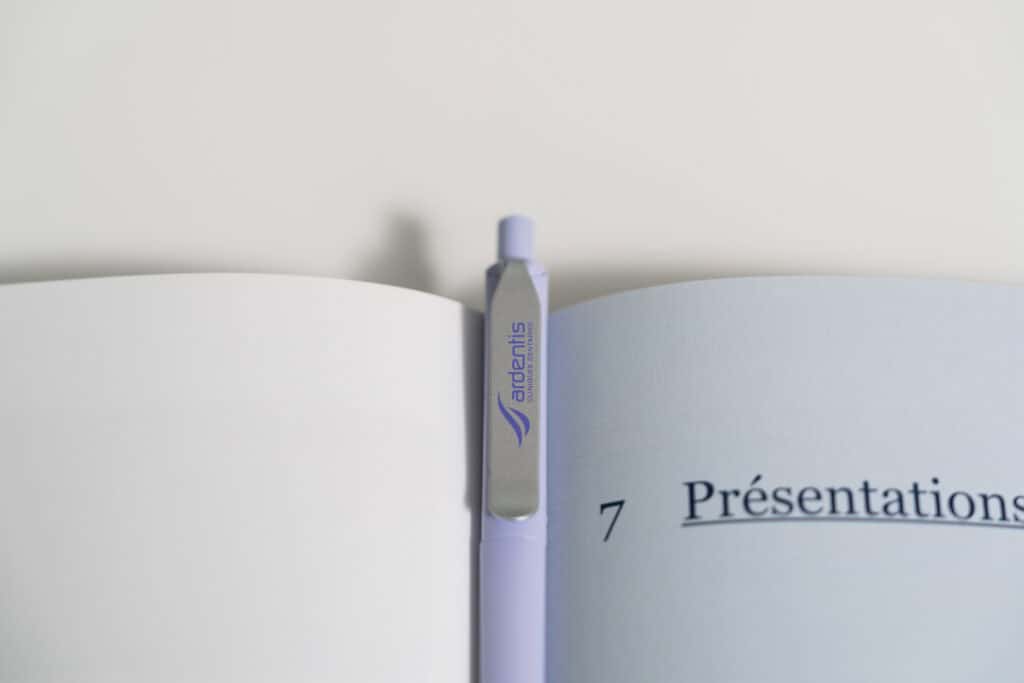 Open presentation book with Ardentis branding and a pen, showcasing professional dental clinic materials.