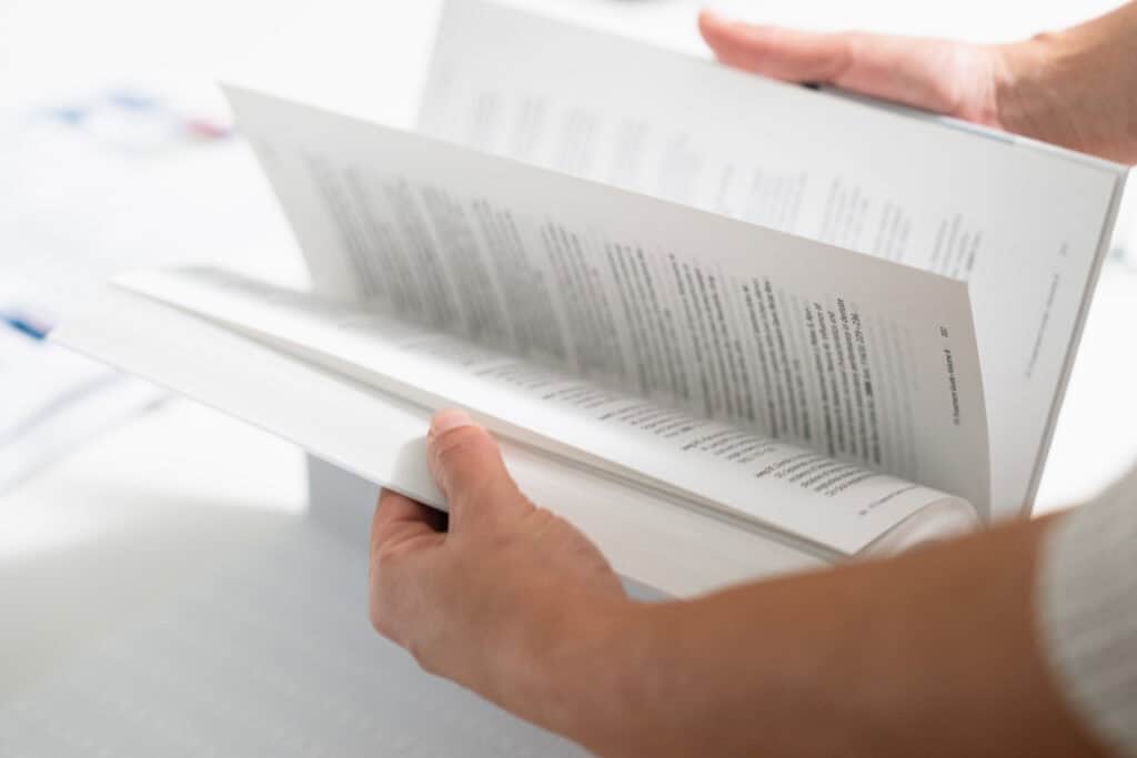 Close-up of a person holding and reading a dental clinic brochure, focusing on patient information and dental care services.