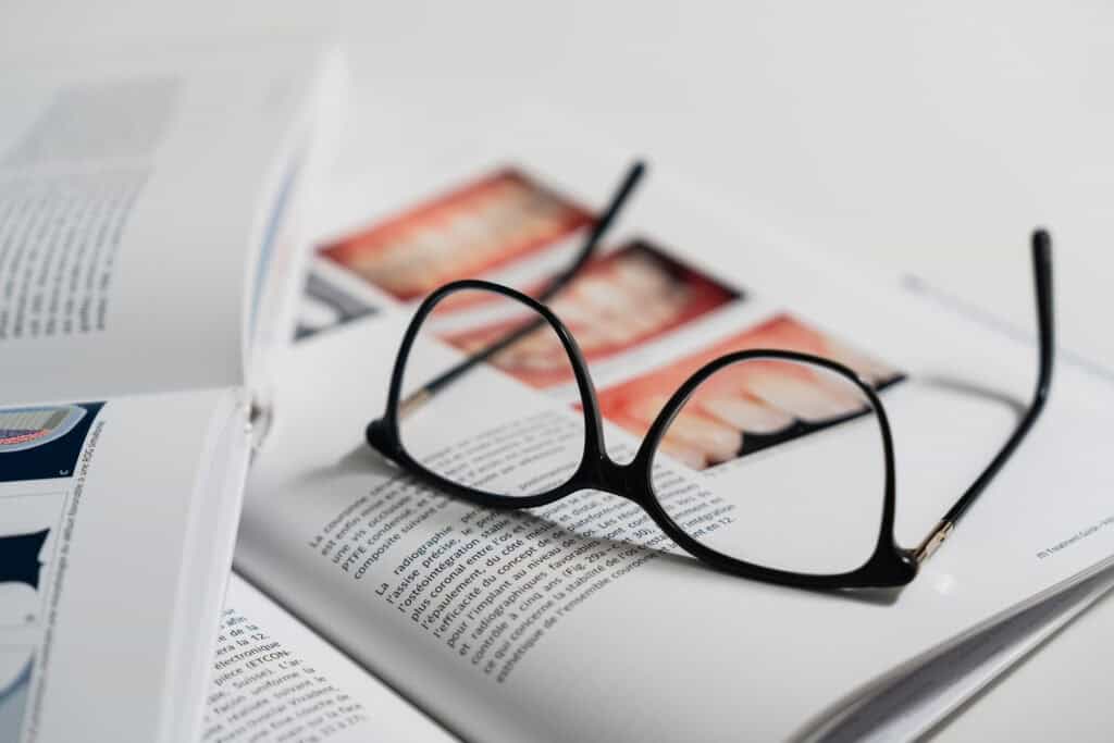 Lunettes posées sur un livre d’implantologie ouvert avec images cliniques