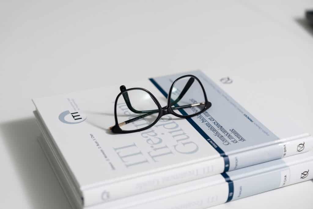 Close-up of eyeglasses resting on a stack of dental textbooks, symbolizing expertise and knowledge in dental care at Ardentis Zurich.