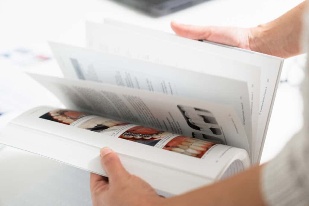 Close-up of a person holding dental brochures and informational materials at Ardentis dental clinic, showcasing patient education resources.