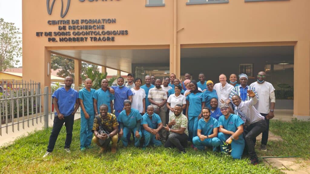 Group photo of dental professionals and staff outside Ardentis dental care center, showcasing a diverse team in front of the clinic building.