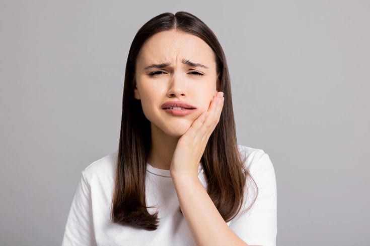 Painful woman holding her jaw, experiencing dental discomfort or toothache.