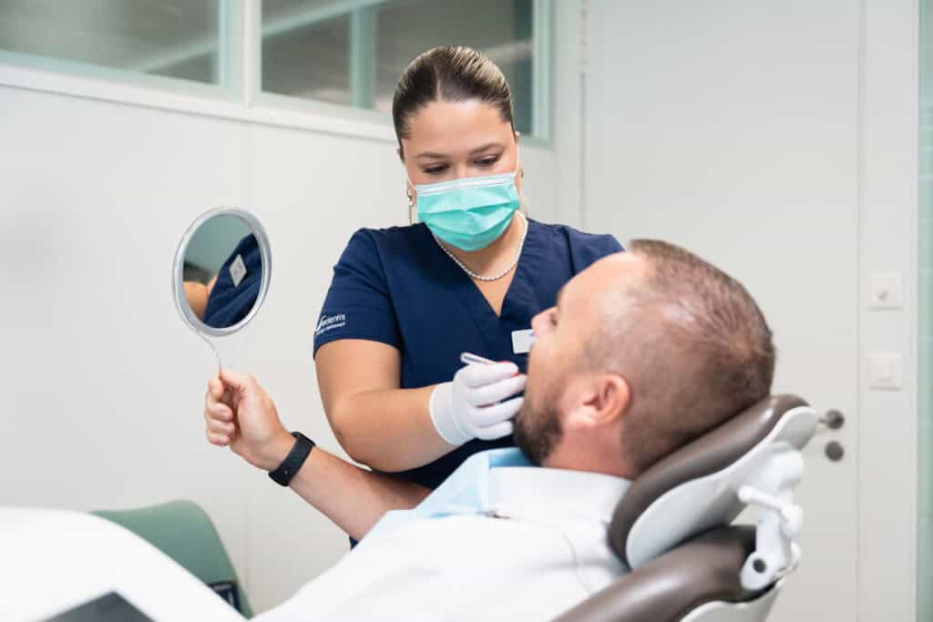 Dental examination at Ardentis clinic with a healthcare professional wearing a mask, examining a patient in a dental chair.