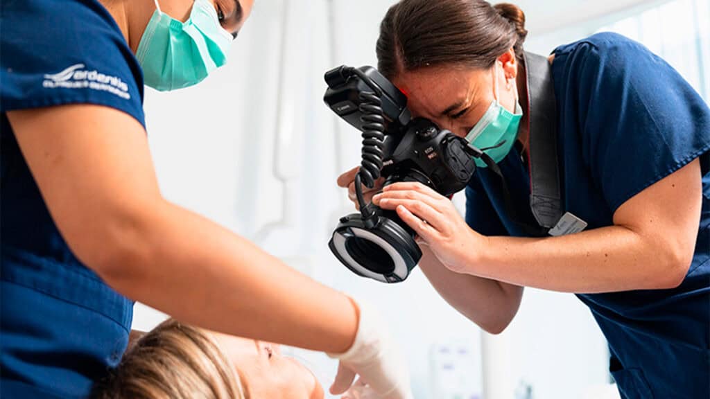 Prise de vue d'une dentiste examinant un patient avec un microscope dentaire dans un cabinet moderne.