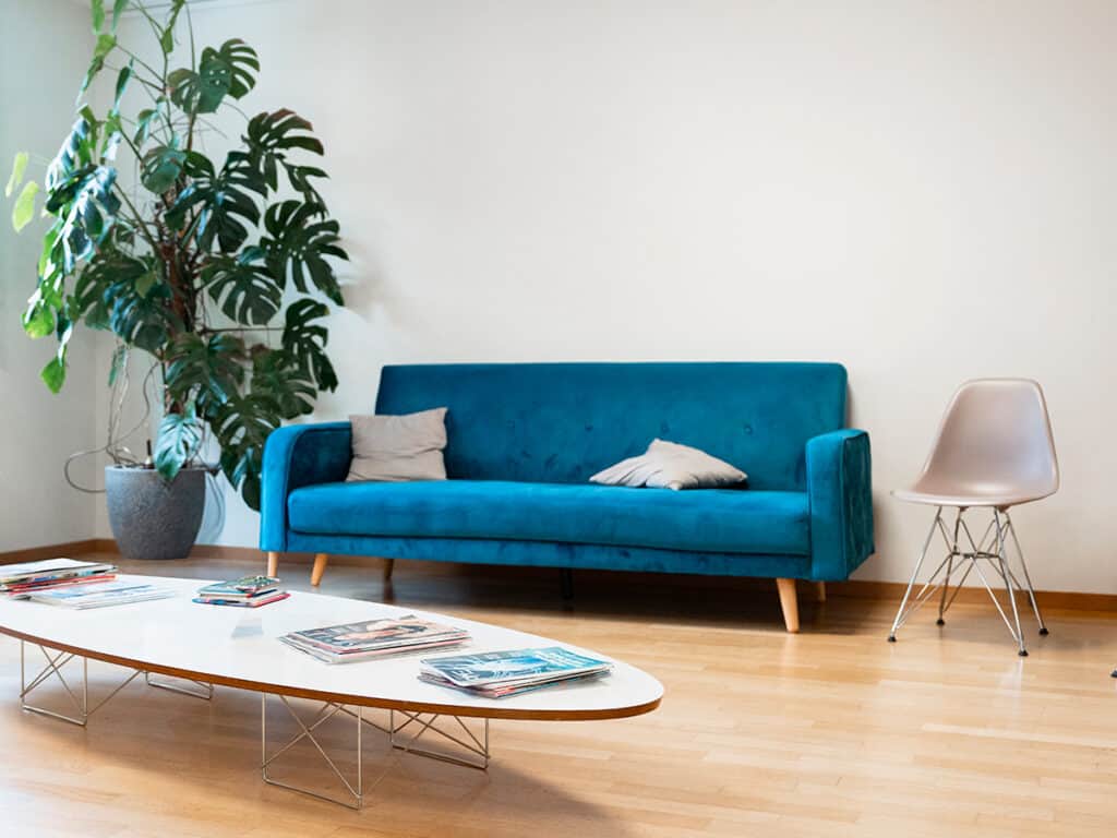 Salon moderne avec canapé bleu, plante verte et table basse élégante, ambiance chaleureuse et accueillante.