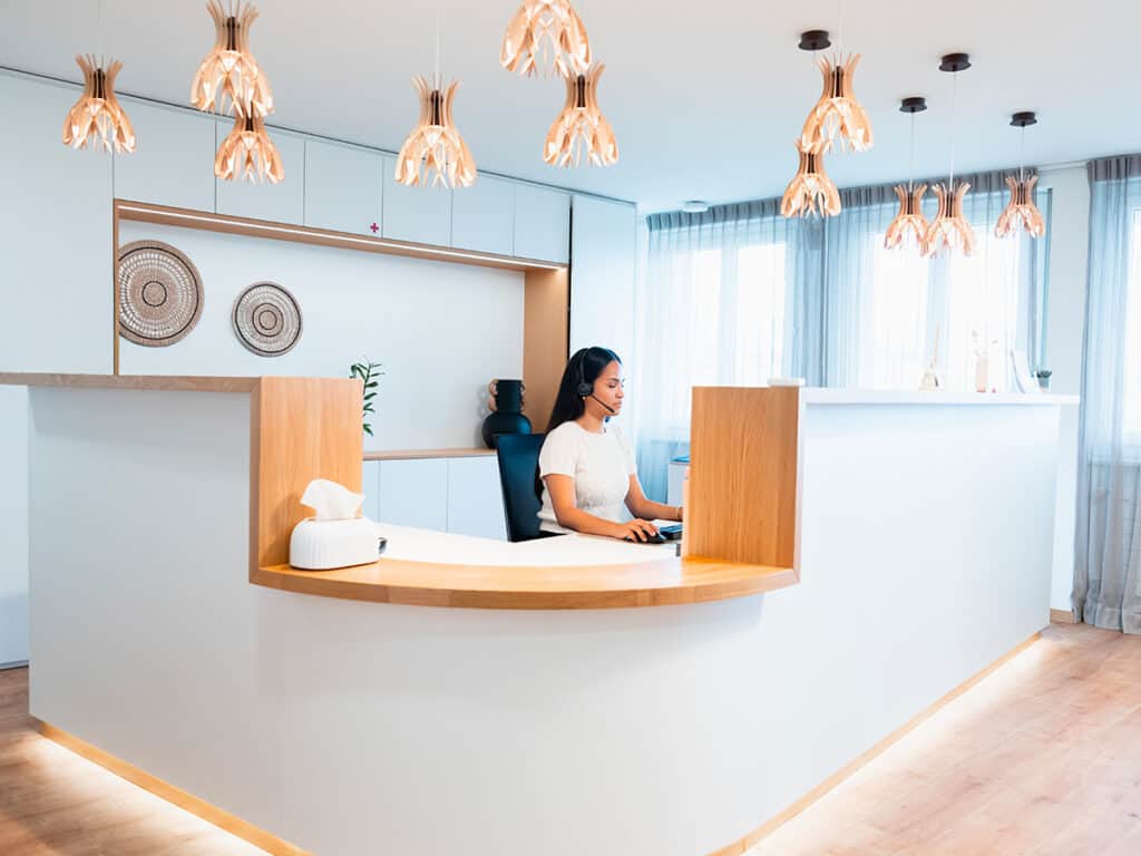 Vue de la réception d'un hôtel moderne Ardentis avec comptoir en bois, éclairage design et ambiance chaleureuse, accueillant les clients dans un espace élégant.