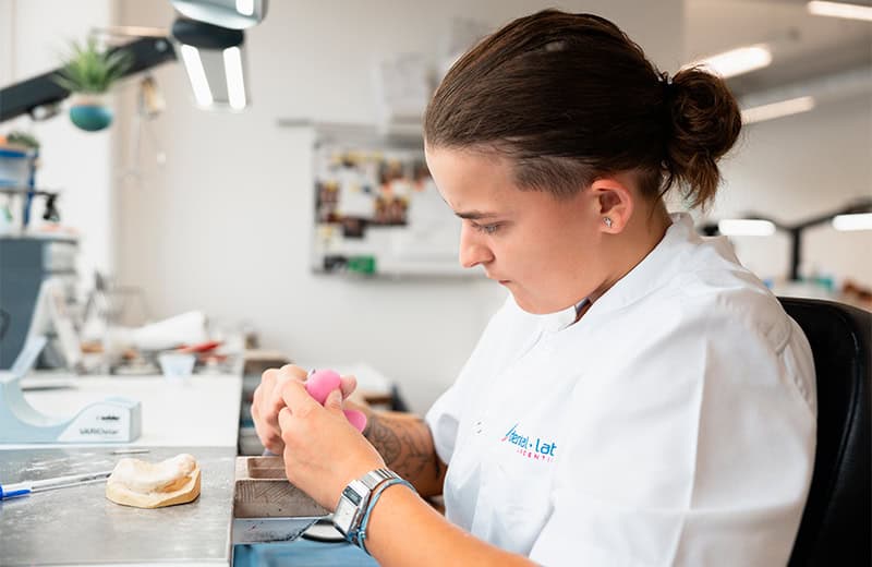Dental technician crafting dental prosthetics in a modern laboratory environment.