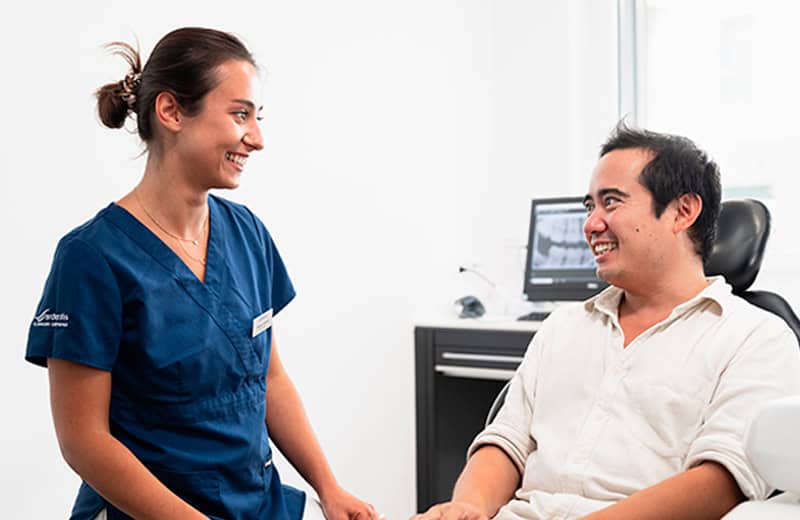 Friendly dentist consultation with a smiling female dental professional and male patient in a modern dental clinic setting.