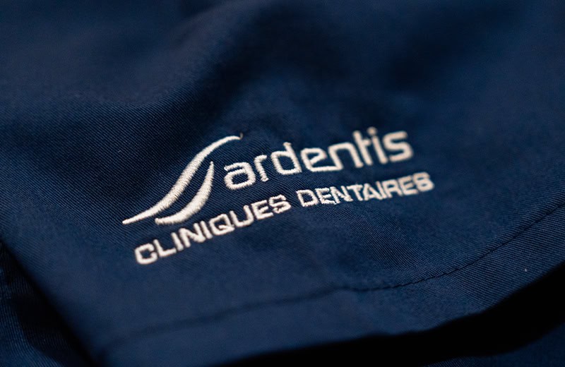 Logo Ardentis Clinique Dentaire sur un uniforme professionnel, mettant en valeur la marque spécialisée en soins dentaires.