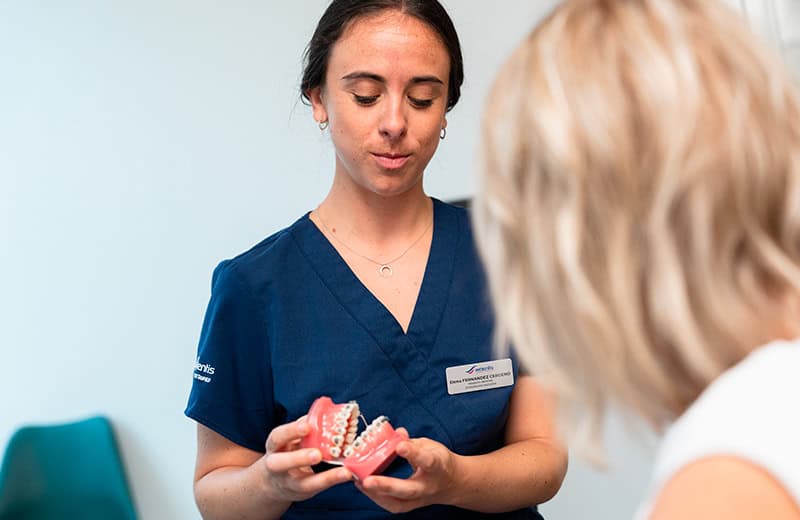 Dental professional showing dental prosthetics and oral health solutions to a patient.
