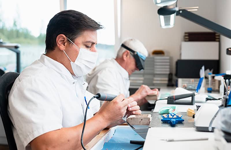 Dental technician crafting dental prosthetics with precision tools in a modern laboratory.
