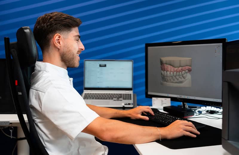 Technicien dentaire travaillant sur une modélisation 3D dentaire sur ordinateur