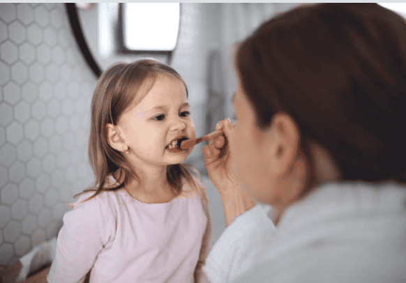 A young girl undergoing a dental examination by a dentist, emphasizing pediatric dentistry and child-friendly dental services.