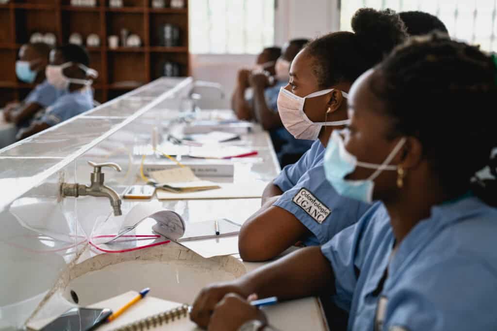 Étudiants en formation médicale portant des masques dans une salle de classe moderne.