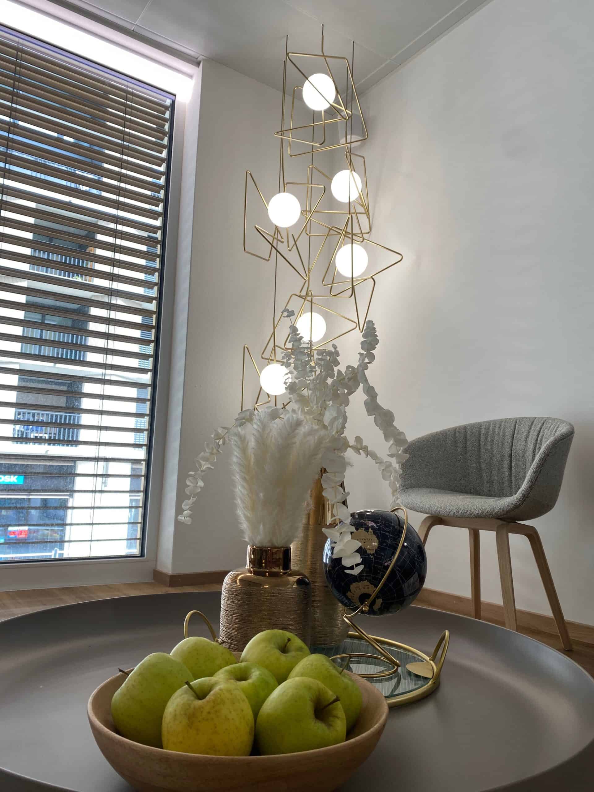 Coin d'attente contemporain avec décoration minimaliste, luminaires design et fruits frais, créant une ambiance accueillante et sophistiquée chez Ardentis.