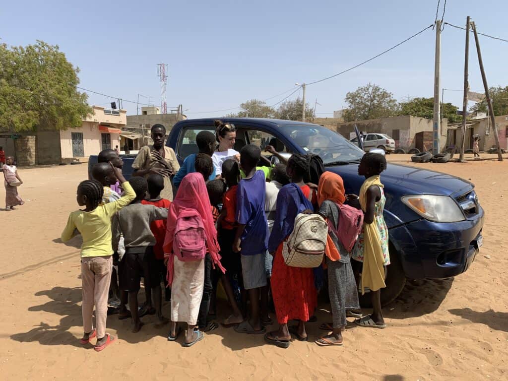 Enfants et enseignant rassemblés autour d'un véhicule dans un village africain.